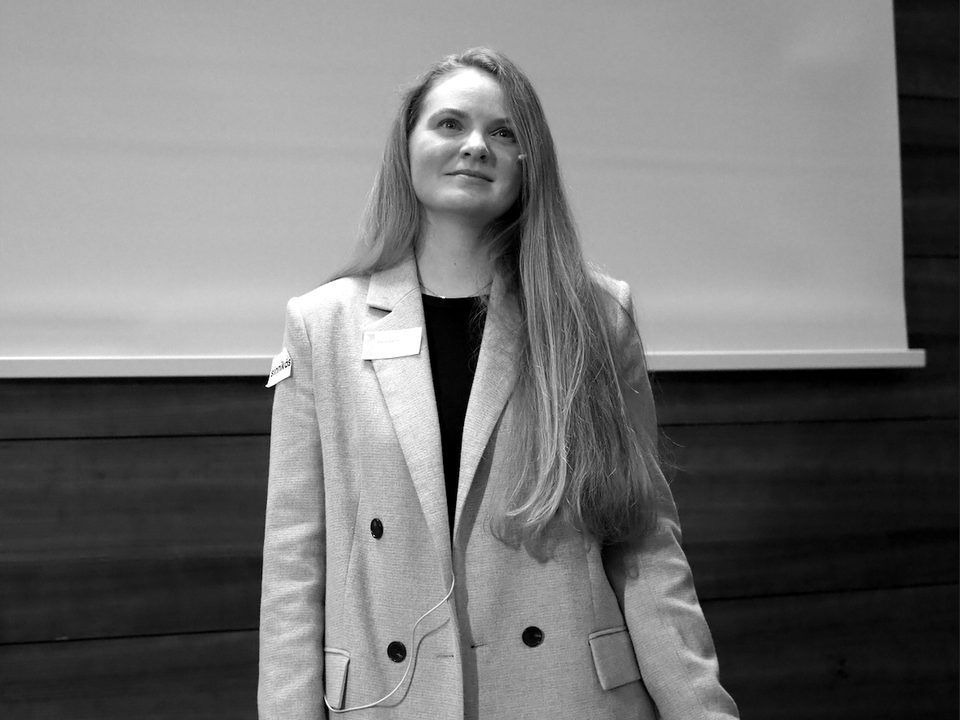 Daria Galina speaking at an event, standing in front of a projection screen